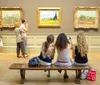 Visitors are viewing and photographing paintings on display in an art gallery