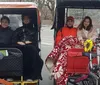 Three passengers are enjoying a ride in a pedal-powered rickshaw while a photographer captures the scene in a park with snow patches on the ground and a lake in the background