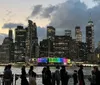 Two people are enjoying a scenic view of a city skyline with their arms raised in a gesture of excitement or freedom