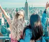 Two people are enjoying a scenic view of a city skyline with their arms raised in a gesture of excitement or freedom