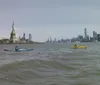 The image shows the view from a kayak on the water near the Statue of Liberty with the New York City skyline in the background