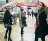 A group of cheerful people pose for a photo on a city sidewalk with one mimicking the mannequins pose in the background