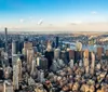 An aerial view showcases a dense array of skyscrapers and buildings in a bustling metropolis with a wide river visible in the background