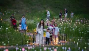 Visitors are enjoying a luminous garden installation at twilight, with one group posing for a photo among the glowing orbs.