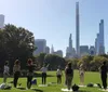 A group of people is participating in an outdoor yoga class in a park filled with trees and enjoying the sunny weather