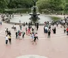 People enjoy a sunny autumn day in a park with a fountain and colorful trees with a backdrop of skyscrapers