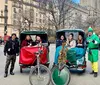 A group of smiling people enjoys a sunny day on a pedicab tour with a view of a tall historic building in the background