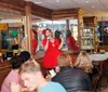 A person in a red dress is performing or speaking into a microphone in front of an audience at an indoor venue