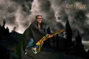 A person is posing with a broomstick as if flying, dressed as a wizard with a castle background and “Harry Potter” text overhead, creating a themed portrait inspired by the Harry Potter series.