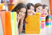 A group of cheerful women is peeking out from behind colorful shopping bags, possibly after a fun shopping spree.