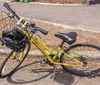 A yellow bicycle with a front basket parked on the side of a path