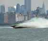 A high-speed boat is creating a large spray of water as it cuts through the waves in front of a cityscape