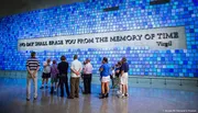 Visitors are viewing a large blue tile art installation with the inscription 