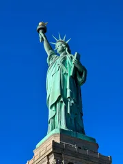 The image shows the Statue of Liberty against a clear blue sky.