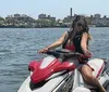 Two people are making peace signs while riding a Yamaha WaveRunner on the water with a city skyline in the background