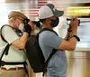 Two individuals are capturing a photograph or video presumably of a moving train as they stand beside a subway platform