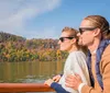 Two people are enjoying a scenic boat ride with a backdrop of colorful autumn foliage