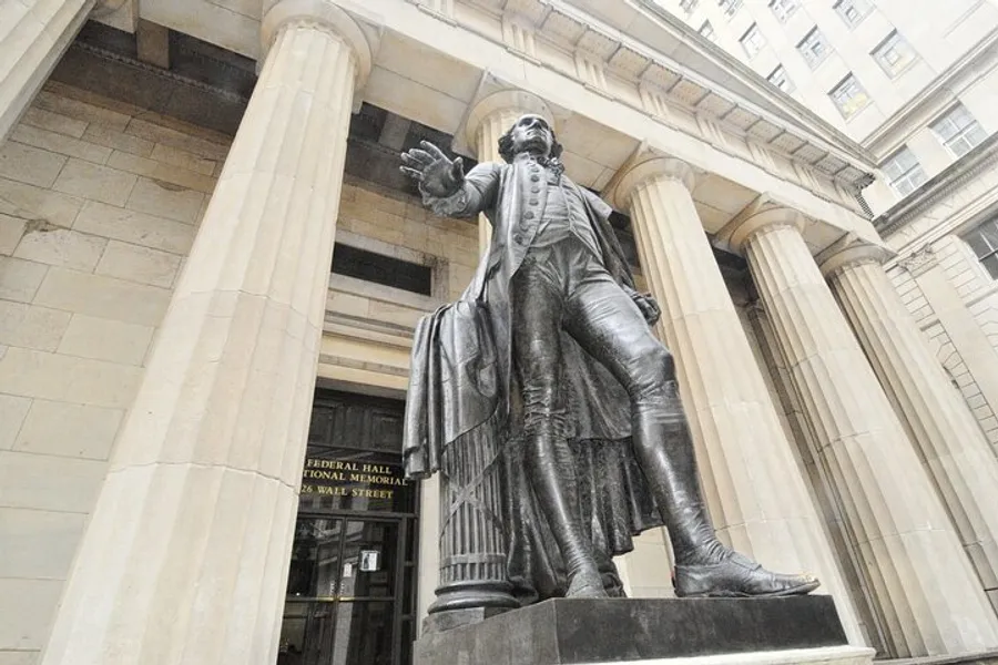 A statue of a historical figure stands prominently before the entrance of the Federal Hall National Memorial on Wall Street.