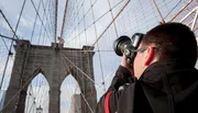 A person is photographing the Brooklyn Bridge in New York City.