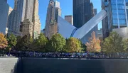 The image shows the Oculus structure at the World Trade Center site in New York City, with a view of the reflecting pool of the National September 11 Memorial and surrounding skyscrapers on a clear day.
