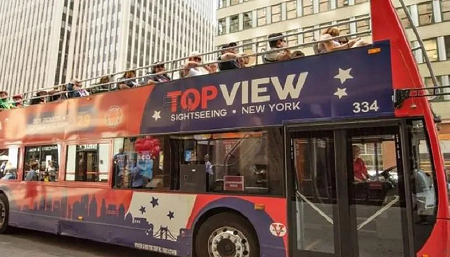 This is a photo of a red double-decker sightseeing bus labeled TopView with tourists on the upper deck, located in New York City.