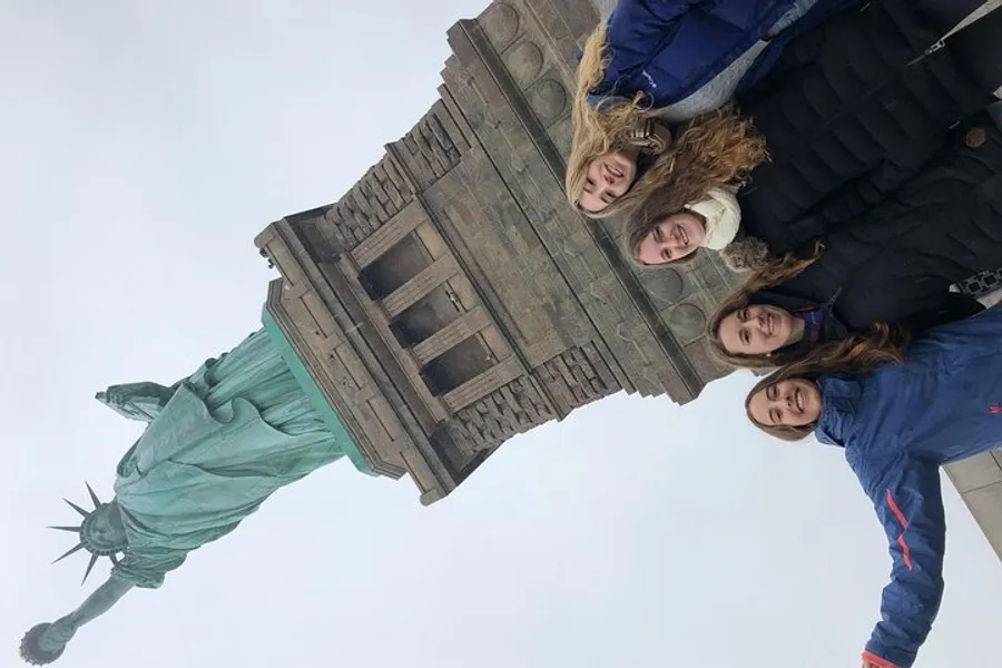 Four individuals are posing for a photo with the Statue of Liberty towering in the background.