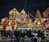 A bustling holiday scene where a crowd gathers in front of festively decorated homes illuminated by Christmas lights and flanked by giant nutcracker statues