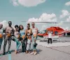 A group of happy people are posing for a photo inside a helicopter with the doors open