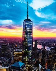 The image features the One World Trade Center skyscraper in New York City against a dramatic sunset with a view of the Hudson River and the surrounding urban landscape.