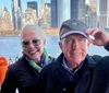 A smiling couple poses for a photo with the New York City skyline in the background