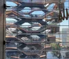 This image shows people enjoying a panoramic view of a city skyline from a high observation deck with glass floor panels