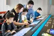 A family is interacting with a digital display at a modern educational exhibit.
