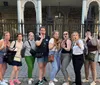 A group of people is playfully posing with exaggerated expressions of shock or surprise in front of a gated building