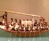 The image shows a detailed model of an ancient Egyptian funerary boat with figures rowing and performing various tasks