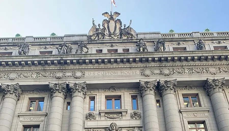 The image shows the ornate facade of the U.S. Custom House with Corinthian columns and detailed sculptures.
