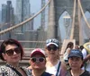 A group of joyful people are posing with raised arms in a bustling Times Square surrounded by bright advertisements and city life