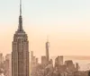 The image features the Empire State Building in the foreground with the skyline of Lower Manhattan in the background bathed in the warm glow of a sunset