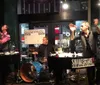 A lively group of people is celebrating and raising their glasses in a bar with live music